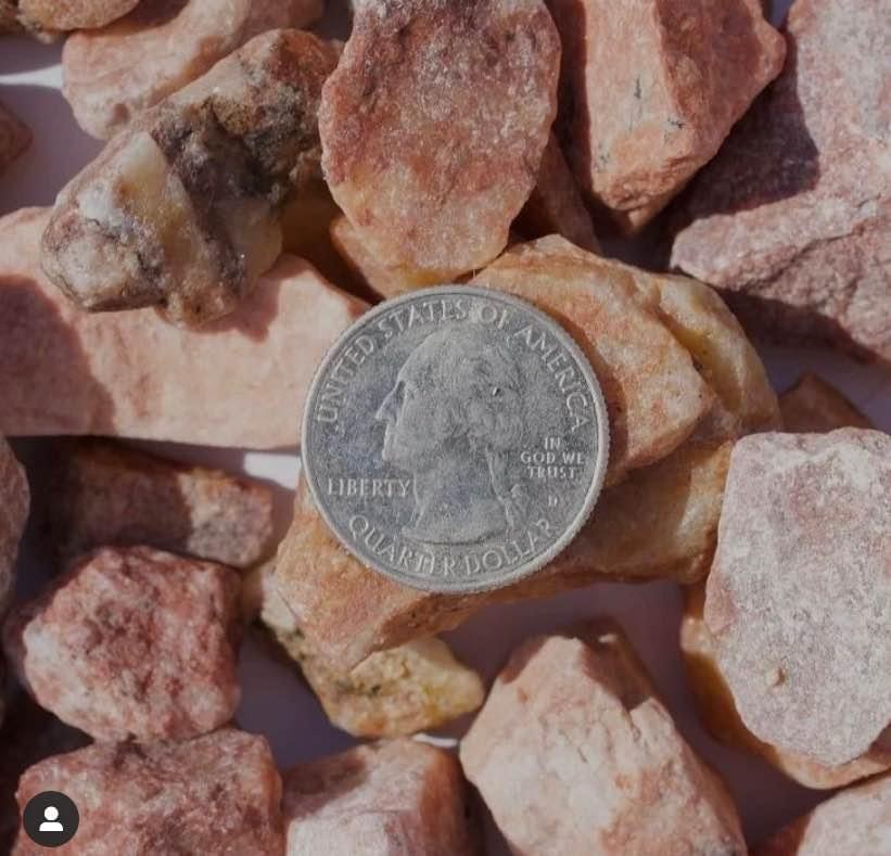 Close-up of South Town rock in warm reds and pinks, with a quarter resting on it for scale