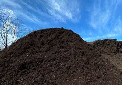 A tall mound of dark rich compost against a blue sky