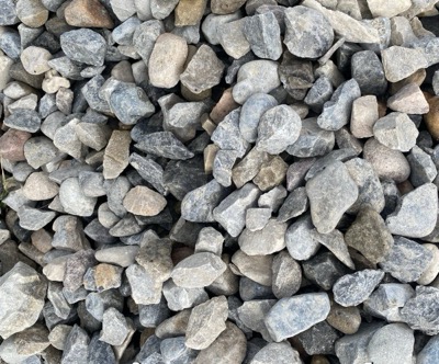 Angular grey drain rock in a range of sizes, with gaps between the stones for water to run through
