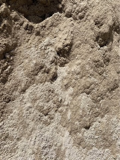 A pile of tan paver sand, fine and dry, in a driveway