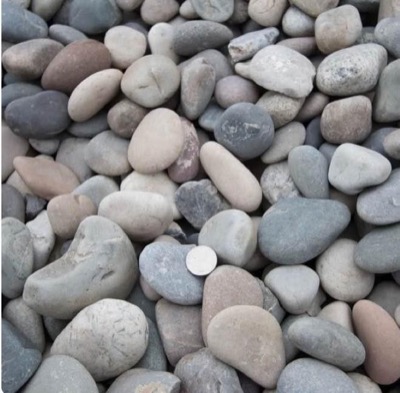 Washed round squeegee pea gravel in soft greys and tans, with a coin for scale